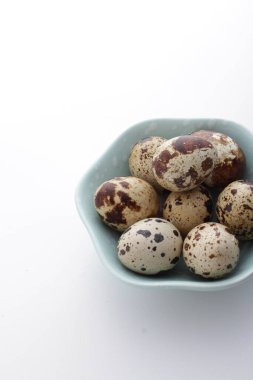 Beyaz arka planda bir kasede bıldırcın yumurtası.