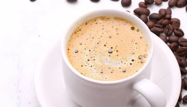 cup of hot coffee with foam and coffee beans