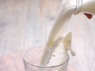 pouring milk into glass on table, closeup clipart