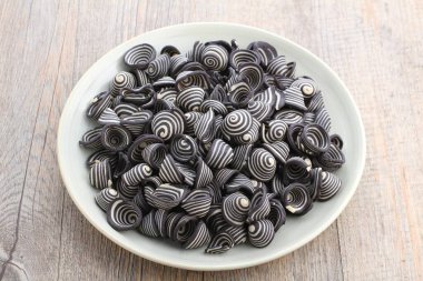 Tahta arka planda çikolata soslu siyah makarna.