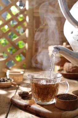 Ahşap arka planda buharlı bir fincan sıcak çay.