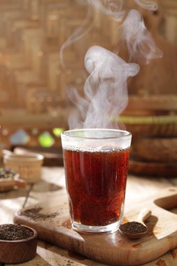 Ahşap arka planda çay, cam bardakta sigara içmek