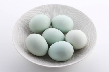 Beyaz arka planda izole edilmiş mavi bir kasedeki yumurtaların yakın plan çekimi.