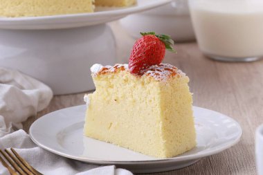 Bir parça pasta ve krema beyaz bir tabakta çatalla