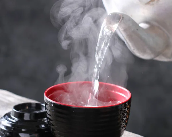 pouring tea into a cup with steam