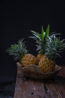 Siyah arka planda ahşap bir kasede taze ananas.