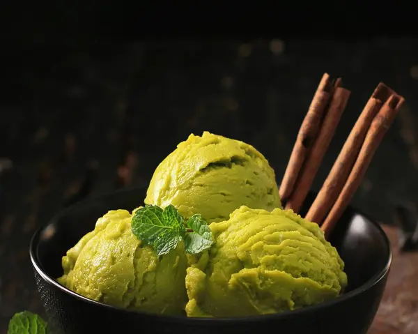 green ice cream in a bowl and with a scoop of mint leaves