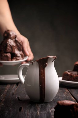 Kadın çikolatayı bardağa dolduruyor, masada lokum var, yakın plan.