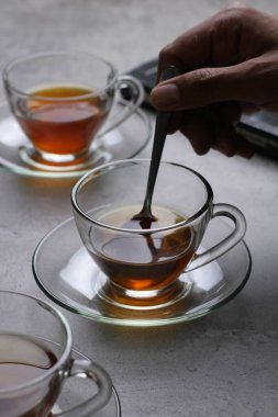 Beyaz bir masada kaşıkla bir fincan siyah çay.