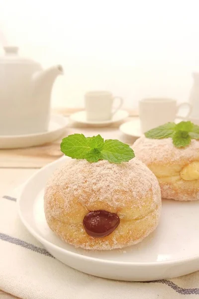 sweet donuts with jam and sugar powder on white plate