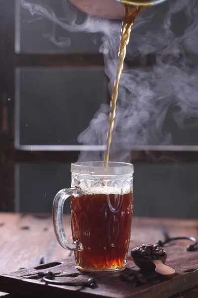 cup of hot tea and steam with smoke on dark background