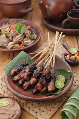 Fıstık soslu keçi satay ya da dilimlenmiş soğan, salatalık ve arnavut biberli soya sosuyla servis edilir.