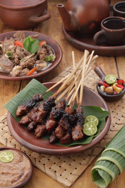 Fıstık soslu keçi satay ya da dilimlenmiş soğan, salatalık ve arnavut biberli soya sosuyla servis edilir.