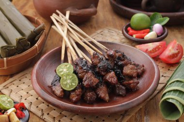 Fıstık soslu keçi satay ya da dilimlenmiş soğan, salatalık ve arnavut biberli soya sosuyla servis edilir.