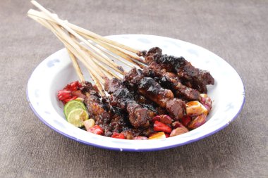 Fıstık soslu keçi satay ya da dilimlenmiş soğan, salatalık ve arnavut biberli soya sosuyla servis edilir.