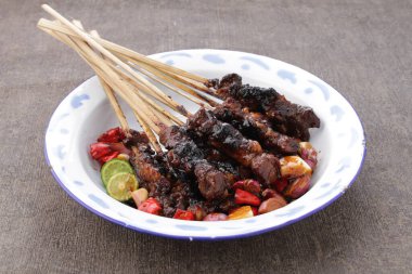 Fıstık soslu keçi satay ya da dilimlenmiş soğan, salatalık ve arnavut biberli soya sosuyla servis edilir.