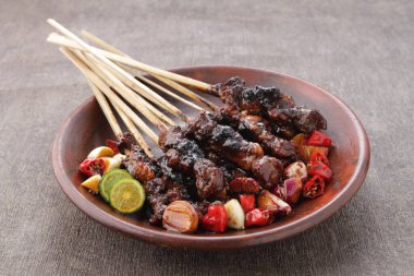 Fıstık soslu keçi satay ya da dilimlenmiş soğan, salatalık ve arnavut biberli soya sosuyla servis edilir.