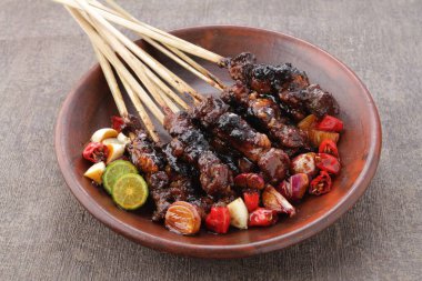 Fıstık soslu keçi satay ya da dilimlenmiş soğan, salatalık ve arnavut biberli soya sosuyla servis edilir.