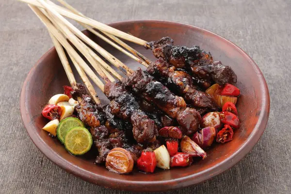 Fıstık soslu keçi satay ya da dilimlenmiş soğan, salatalık ve arnavut biberli soya sosuyla servis edilir.