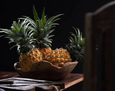 Siyah ahşap bir masanın üzerindeki kasede ananas.