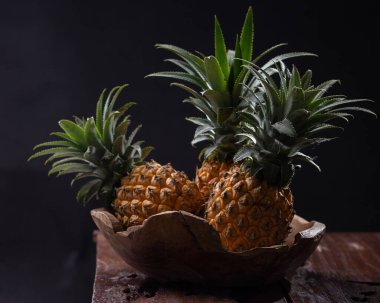 Taze ananas ahşap kasede siyah zemin üzerinde fotokopi alanı ile