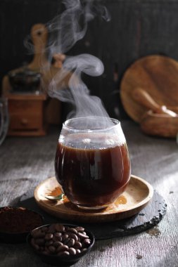 Kahve fincanı ve kahve çekirdekleri ahşap masada.