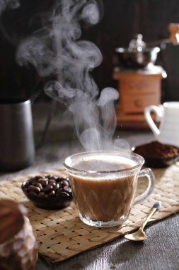 Kahve çekirdekleri ve fincanda süt olan sıcak kahve.