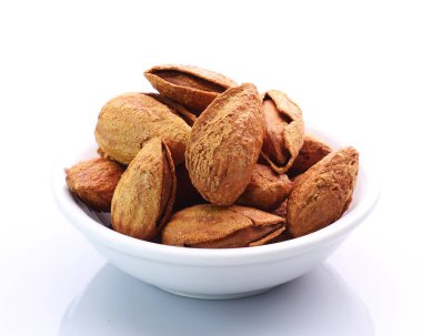 Beyaz arka planda bir kasede badem.