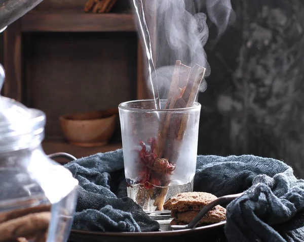 glass of coffee with ice and cinnamon on a wooden background