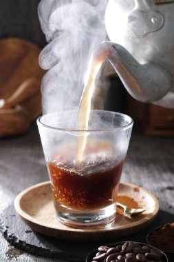 Bir fincan kahve dolduran bir çaydanlık.