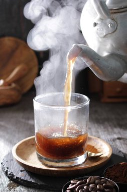 Bir çaydanlık bardağa çay dolduruyor.