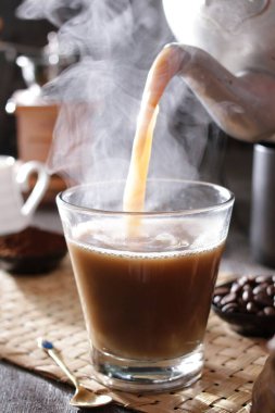 Bardağa doldurulan bir fincan kahve.