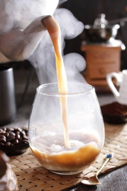 Bir insan bardağa bir fincan kahve dolduruyor.
