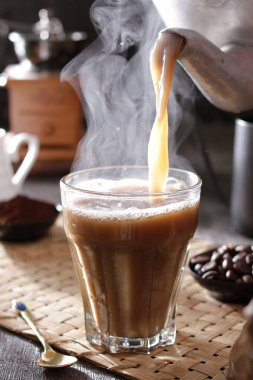 Bardağa doldurulan bir fincan kahve.