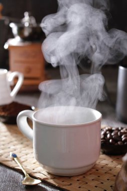 Masanın üzerinde dumanı tüten bir fincan kahve.