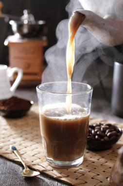 Bir insan bardağa bir fincan kahve dolduruyor.