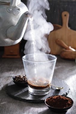 bir çaydanlık bardağa su dolduruyor.
