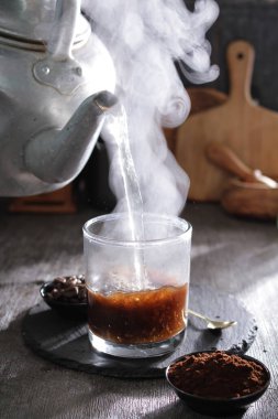 Bir çaydanlık bardağa çay dolduruyor.