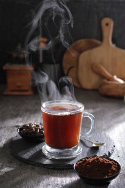 Bir fincan sıcak çay kaşığı ve kaşığı masada dinleniyor.