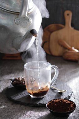 bir çaydanlık bardağa su dolduruyor.