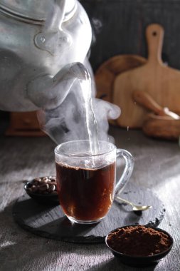 bir çaydanlık bardağa su dolduruyor.