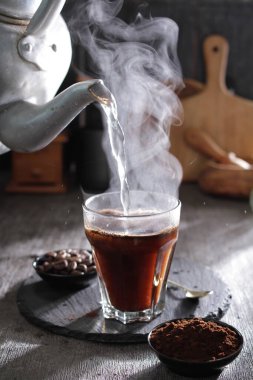 bir çaydanlık bardağa su dolduruyor.