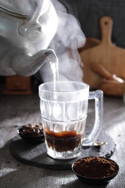 Bardağa doldurulan bir fincan kahve.