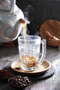 Bardağa doldurulan bir fincan kahve.