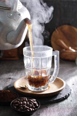 Bardağa doldurulan bir fincan kahve.