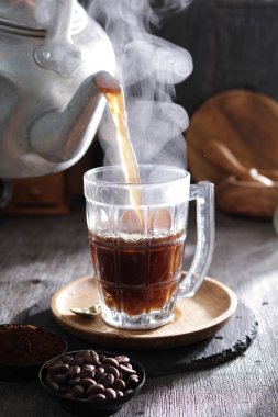 Bardağa doldurulan bir fincan kahve.