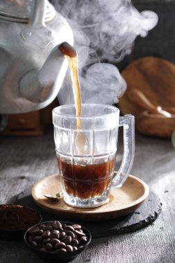 Bardağa doldurulan bir fincan kahve.