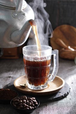 Bardağa doldurulan bir fincan kahve.