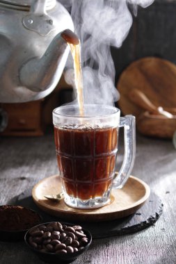 Bardağa doldurulan bir fincan kahve.