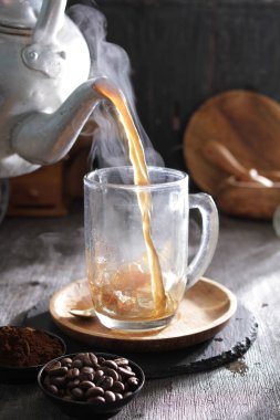 Bardağa doldurulan bir fincan kahve.